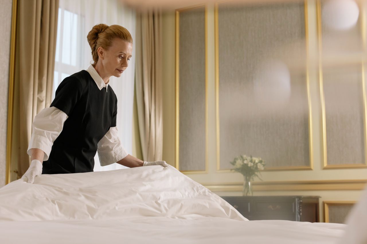 why-choose-us A professional housekeeper fixes a bed in a luxurious hotel room.